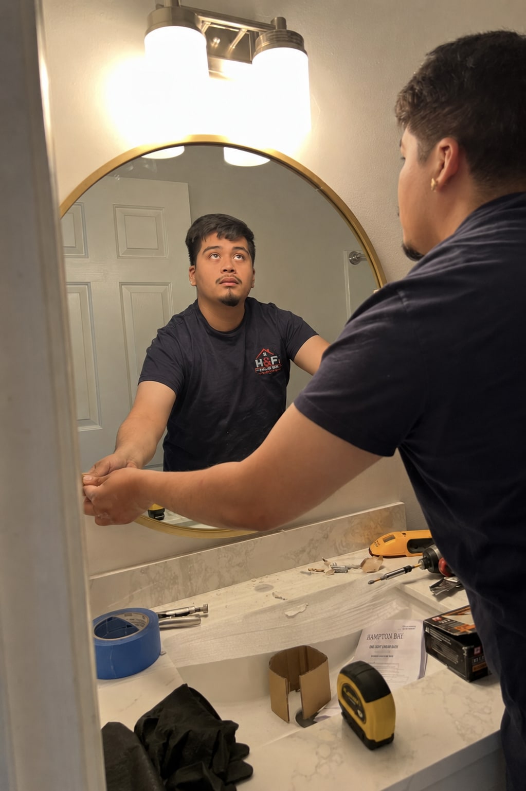 Hugo, founder and lead handyman of H&F Tri-State Handyman, installing a bathroom mirror